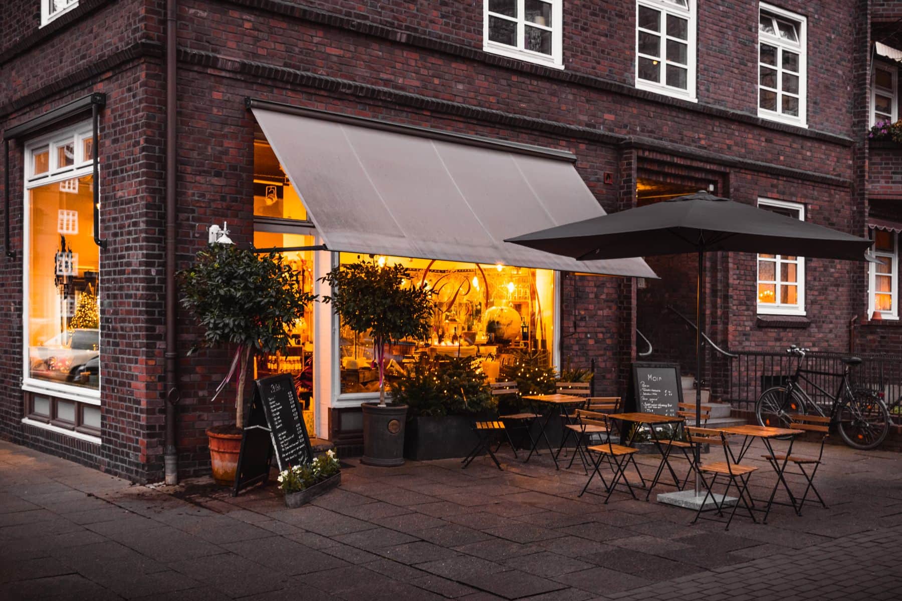 A restaurant storefront in the evening with guests arriving